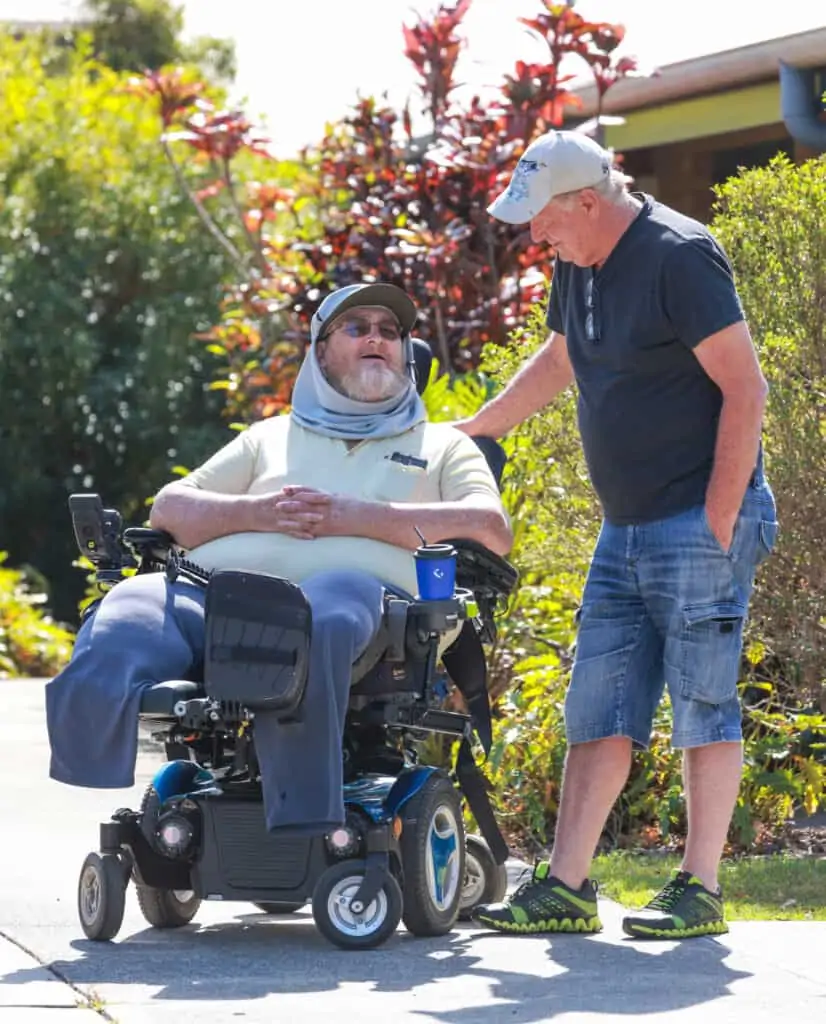 Two men talking to each other, one is in a wheelchair demonstrating supported independent living