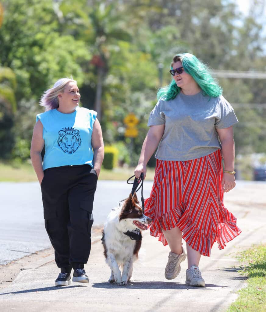 Two woman walking together, one has a dog on a leash