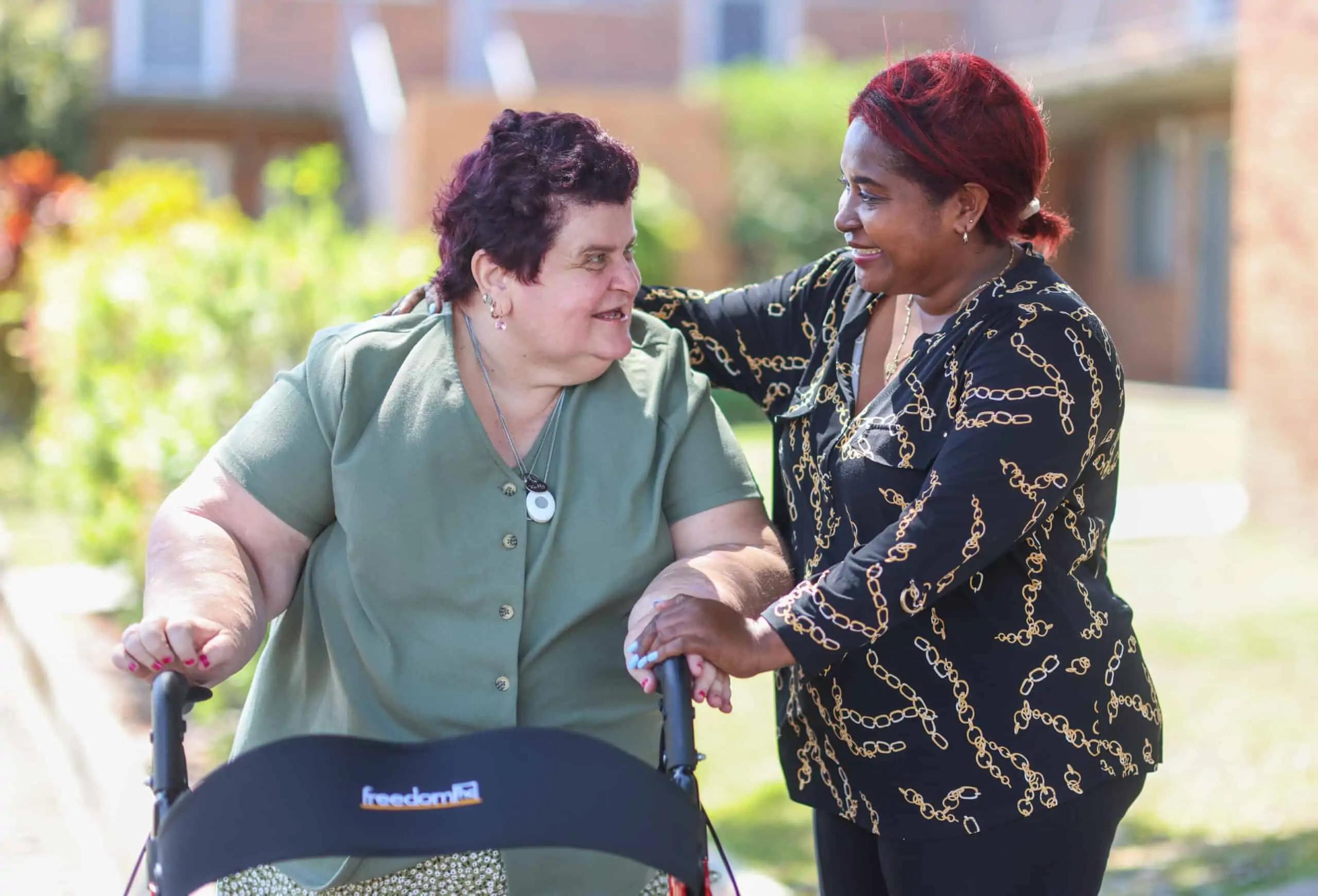 Woman with a walker being supported by personal carer