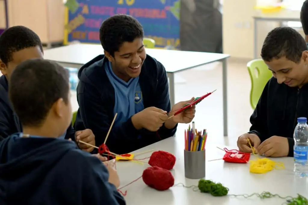 Group of 4 boys at school doing an arts and crafts activity, smiling and laughing